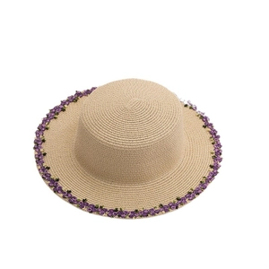 Beige wide brim straw sun hat with decorative purple flower trim for summer beach outings