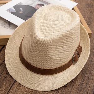 Detail of woven straw fedora hat with a brown faux leather belt and metal buckle