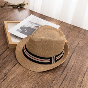 Détail d'un chapeau de paille classique avec ruban rayé sur table en bois