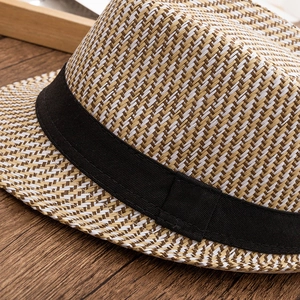 Detailed close-up of the fine woven texture and black decorative band on this straw fedora