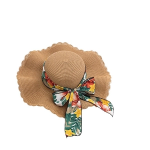 Straw sun hat with wavy brim and floral ribbon bow decoration for summer beach