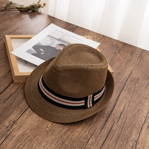 Chapeau Fedora en paille marron foncé pour homme avec ruban rayé sur bureau en bois