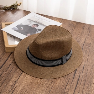 Detail of dark brown woven straw hat with black and white checkered ribbon on wood surface