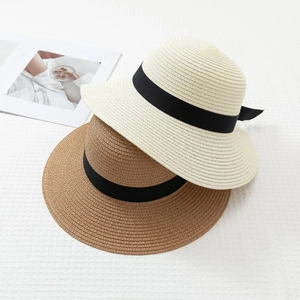 Detail of woven straw sun hats in beige and brown with black satin bow ribbons