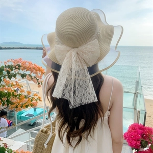 Beige straw sun hat with lace bow and pearls, elegant wavy brim for beach vacation