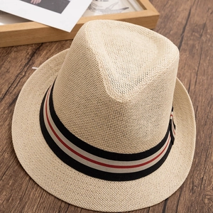 Détail d'un chapeau de paille beige classique avec ruban rayé noir et rouge sur bois