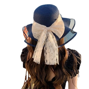 Navy blue straw sun hat with large lace bow and wavy brim for women outdoors
