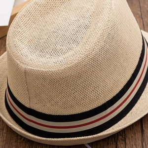 Gros plan sur la texture du chapeau de paille et le ruban rayé sur bois sombre