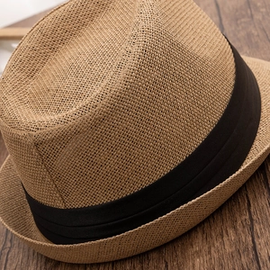Detailed close-up of khaki straw hat weave with a black ribbon band on wooden surface