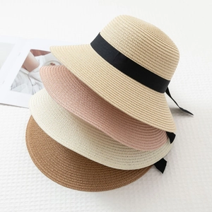 Straw sun hats with bow ribbons in beige, white, pink, and brown for summer beach travel