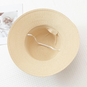 Detailed texture of the woven straw sun hat featuring a white elastic chin strap