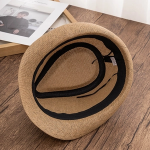 Detail view of the straw fedora interior featuring a black sweatband and a material care label