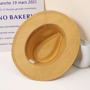 Detail of the yellow paper straw hat interior featuring a sweatband and washing label