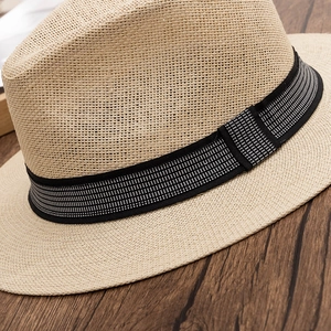 Close-up of woven paper straw texture and black-and-white checkered ribbon on fedora hat