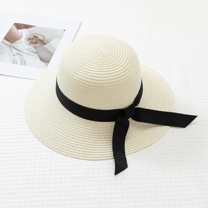 Detail of beige straw hat featuring delicate weaving texture and black silk ribbon bow