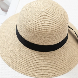 Close-up of natural beige straw sun hat with black ribbon and tight weave detail