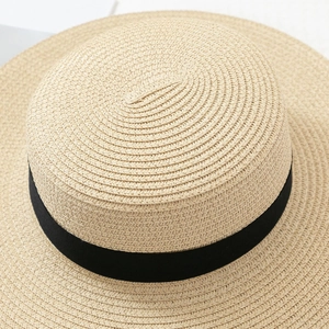 Detail of the woven texture and black ribbon on a straw boater sun hat for women