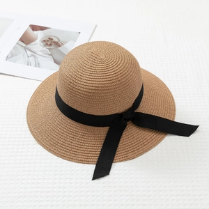 Straw sun hat with wide brim and black ribbon bow for summer beach travel
