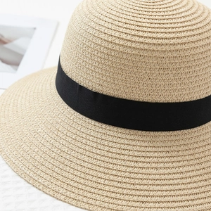Detailed close-up of woven paper straw texture and black ribbon trim on sun hat
