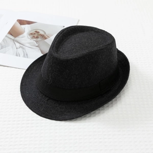 Top view of a dark grey wool fedora hat with black ribbon on white waffle texture
