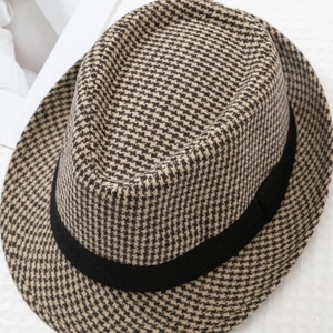 Detailed view of the brown houndstooth pattern and black ribbon on a classic fedora hat