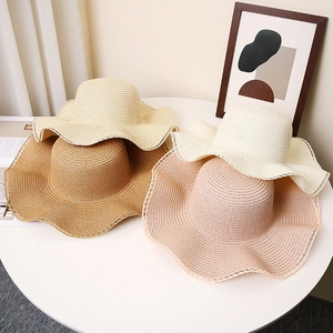 Detail of four colorful wide-brim straw hats with wavy lace edges on a white table