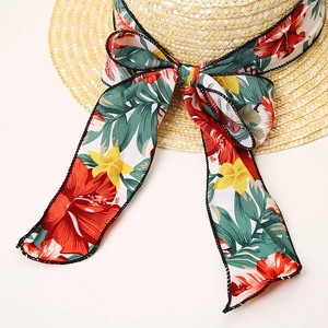 Women's straw sun hat with large tropical floral ribbon and elegant bow for summer beach