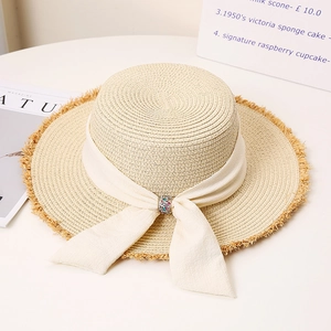 Close-up of women straw sun hat with frayed edge and rhinestone ribbon detail