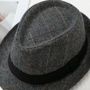 Detailed macro shot of vintage grey herringbone tweed fedora with orange windowpane pattern