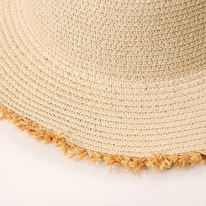 Close-up of the woven straw texture and stylish raw fringe edge on a sun beach hat