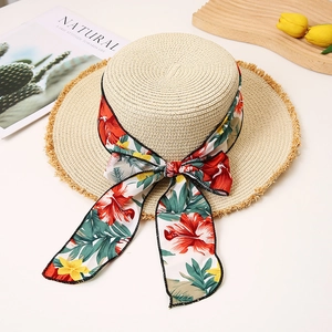 Detail of flat top straw hat with floral chiffon ribbon and frayed edge on white background