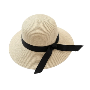 Beige woven straw sun hat with wide brim and black ribbon bow for summer beach travel