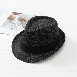 Detailed texture of dark gray wool fedora hat with black band on a white fabric background