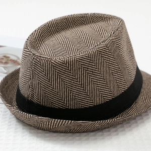 Close-up of brown herringbone fedora hat with a black band on a textured background