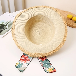 Detail of hand-woven straw sun hat with floral silk scarf and elegant frayed wide brim