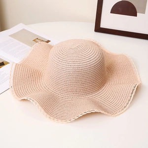 Detailed close-up of beige straw sun hat featuring elegant white lace on wavy wide brim
