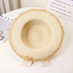 Close-up of beige straw hat featuring fine weave textures and stylish frayed edge details