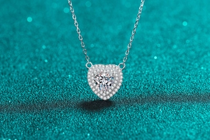 Gros plan d'un collier cœur en argent S925 avec moissanite double halo sur fond pailleté