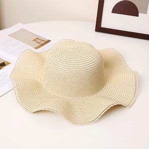 Detailed close-up of straw sun hat featuring wavy brim and delicate white lace trim details