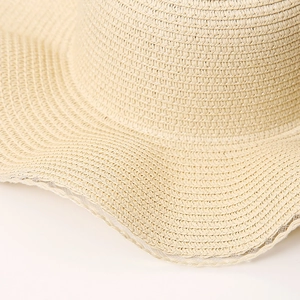 Detailed close-up of woven straw texture and wavy brim design on this summer beach hat