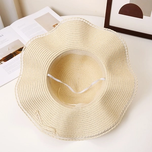 Detail view of woven straw sun hat interior with elastic wind rope and wavy brim