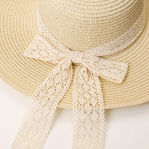 Detailed view of the straw hat weaving texture and delicate white lace bow tie detail