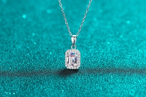Macro view of radiant cut emerald pendant necklace with halo of small diamonds