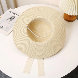 Detail of a wide brim straw hat with elegant lace ribbons and interior windproof strap