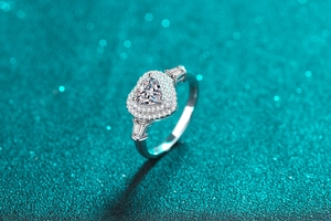 Macro detail of heart-cut moissanite ring with side baguette stones and halo setting
