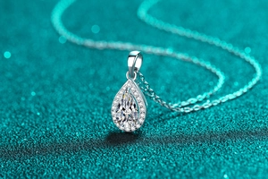 Macro shot of pear-shaped moissanite pendant with halo diamonds on a silver chain