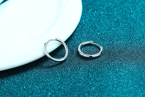 Dettaglio di orecchini a cerchio in argento S925 lucido con design moderno a cerniera