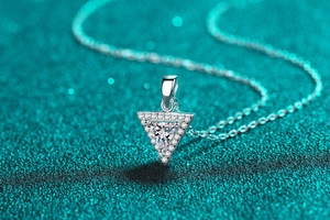 Macro shot of triangle moissanite pendant with halo diamonds on green glitter