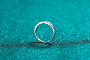 Macro shot of minimalist S925 sterling silver ring with moissanite on glitter background