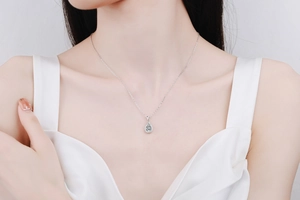 Close-up of S925 sterling silver necklace with pear-cut moissanite pendant on model